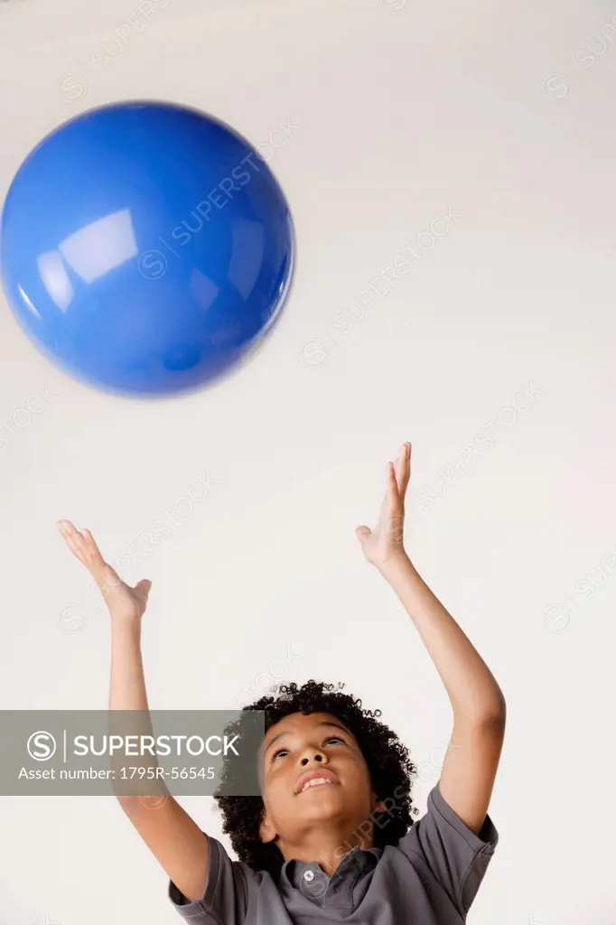 Studio shot of boy 8_9 tossing blue ball