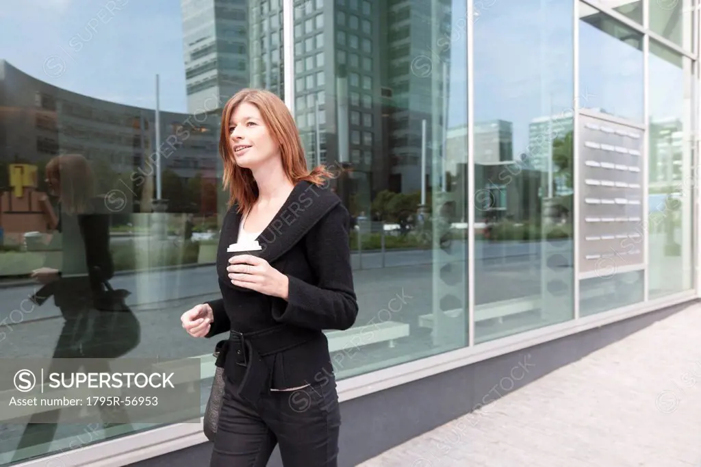 The Netherlands, Amsterdam, Businesswoman walking with coffee