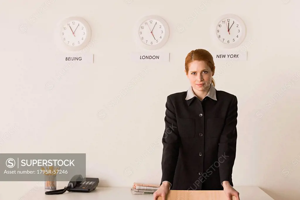 Portrait of businesswoman with world clocks behind