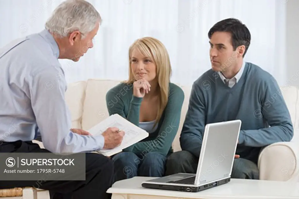 Businessman talking to couple in home
