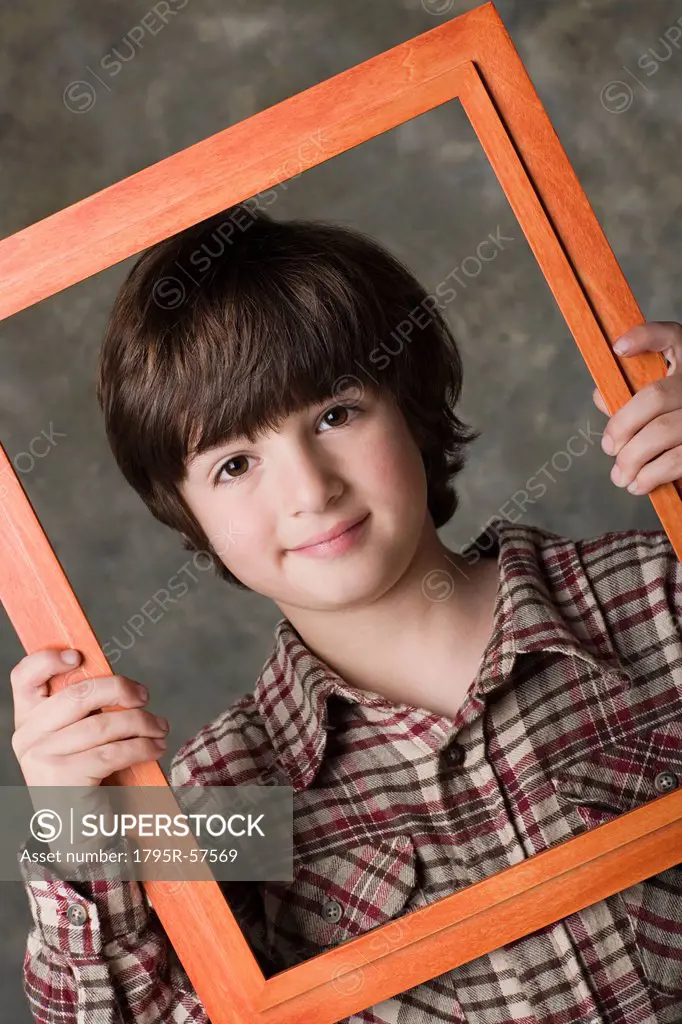 Portrait of boy 6_7 looking through frame, studio shot