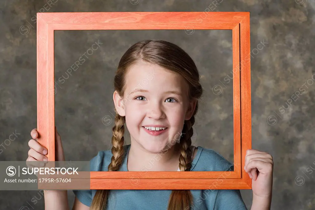 Portrait of smiling girl 8_9 holding frame, studio shot