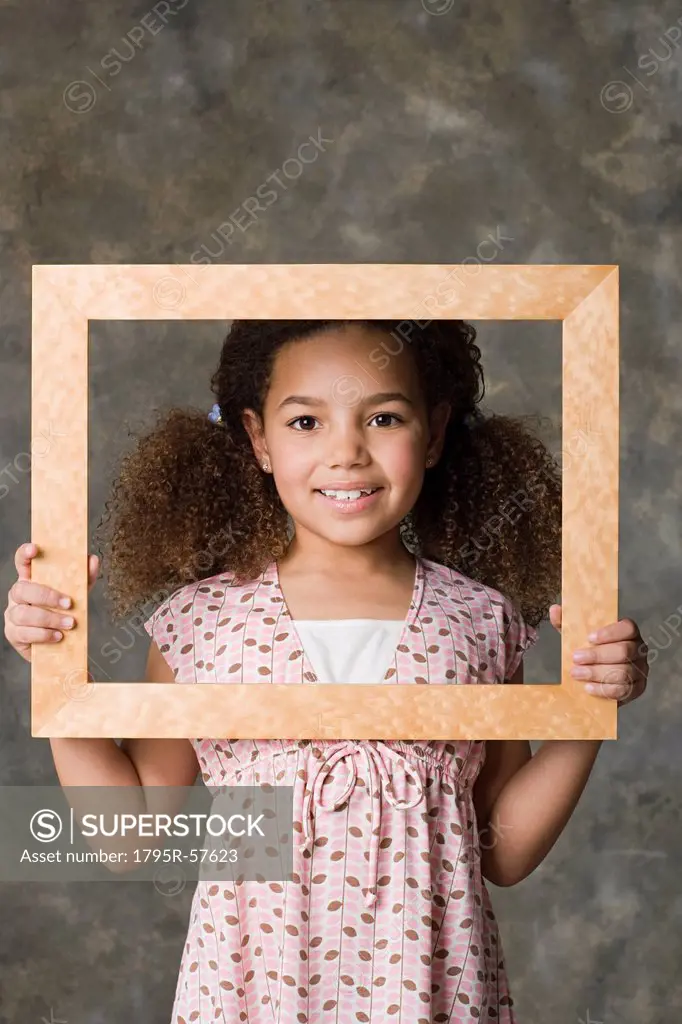 Portrait of smiling girl 8_9 holding picture frame, studio shot