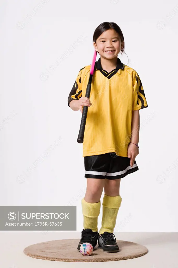 Portrait of smiling girl 8_9 wearing field hockey costume, studio shot