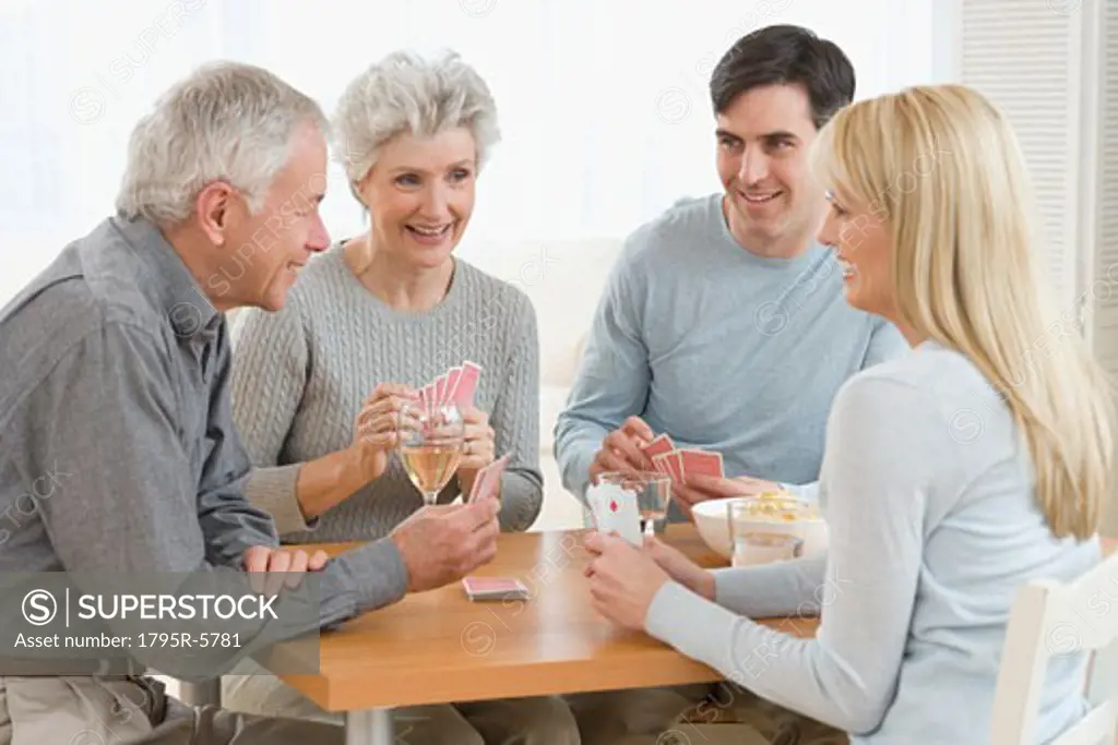 Senior couple and young couple playing cards