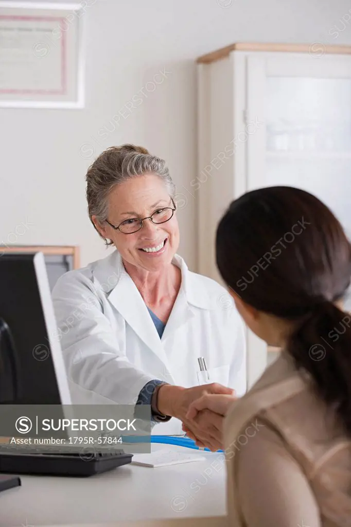 Smiling female doctor shaking hand with patient in her office
