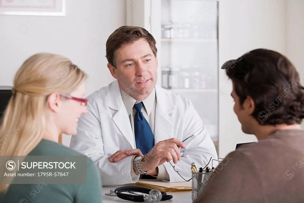 Male doctor talking to patients in his office