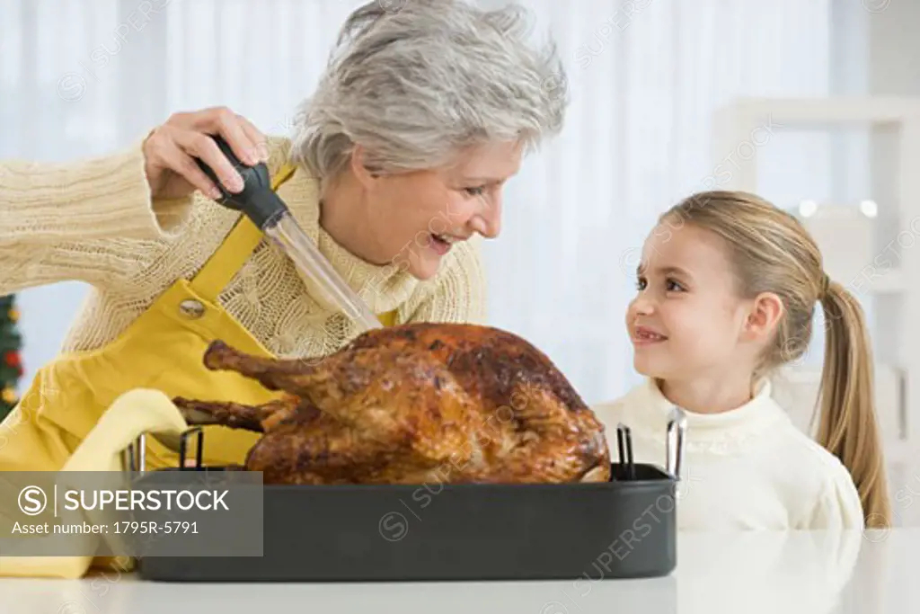 Grandmother and daughter basting roast turkey