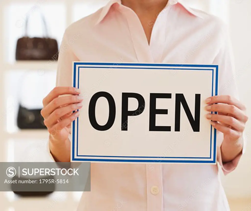 Woman holding Open sign in boutique
