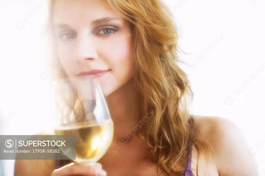 Portrait of young woman smelling wine, studio shot