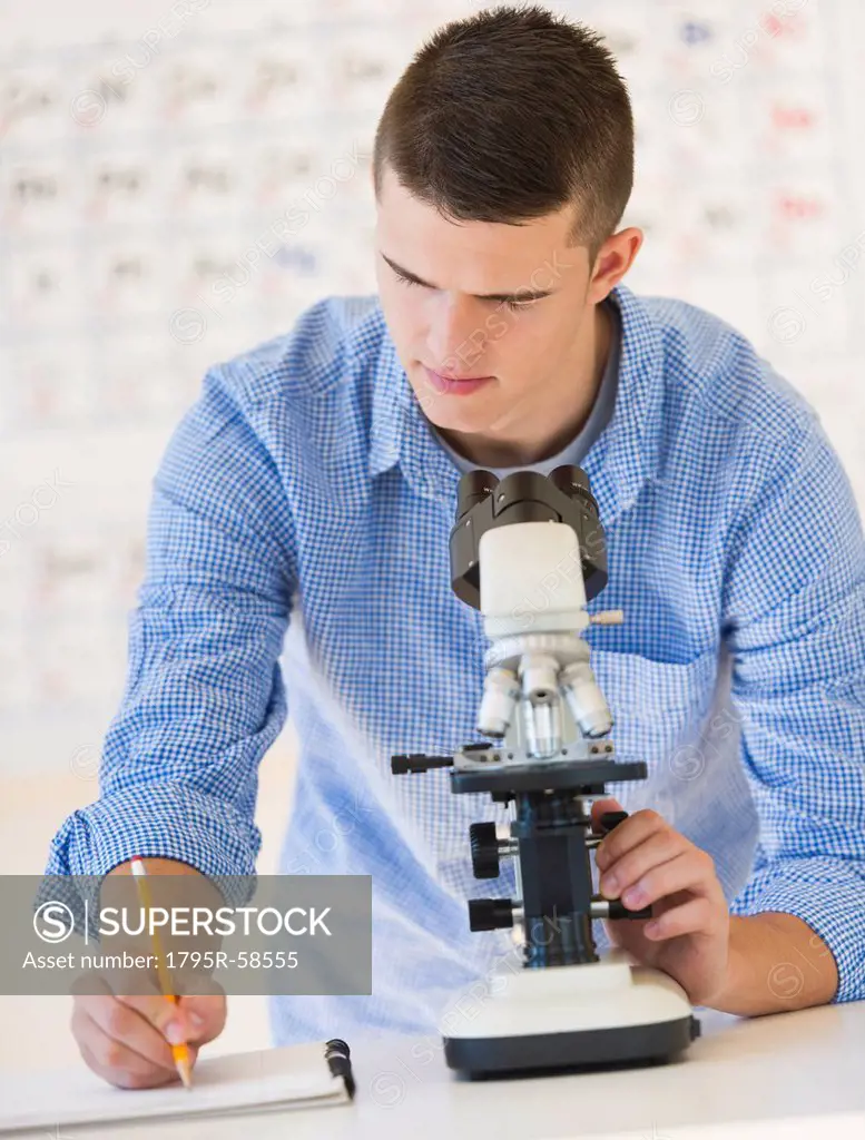 Teenage student 16_17 with microscope doing notes