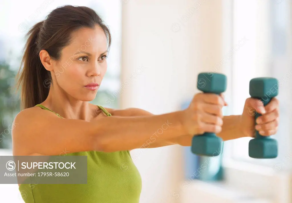 Mid adult woman training with dumbbell