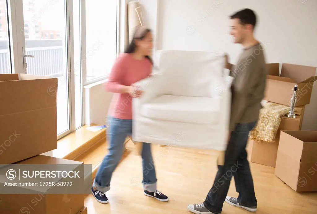 Man and woman carrying chair in new house