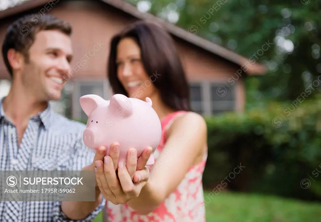USA, New York, Putnam Valley, Roaring Brook Lake, Couple holding piggy bank