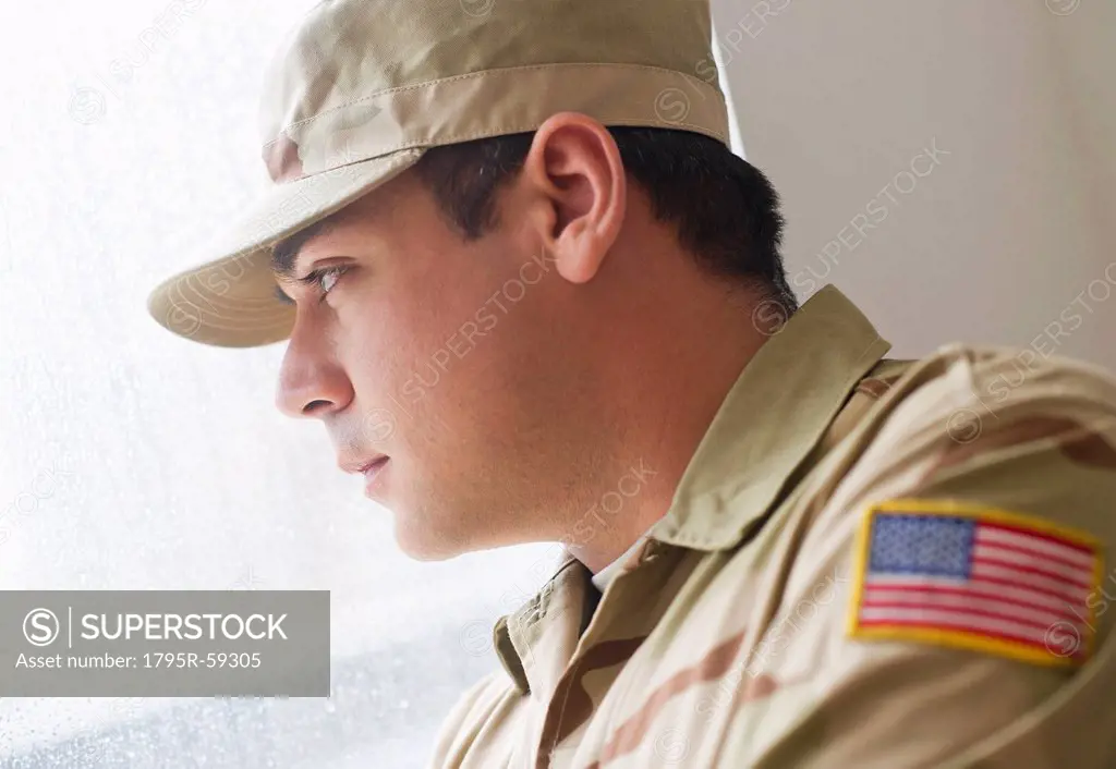 Man wearing military uniform looking through window