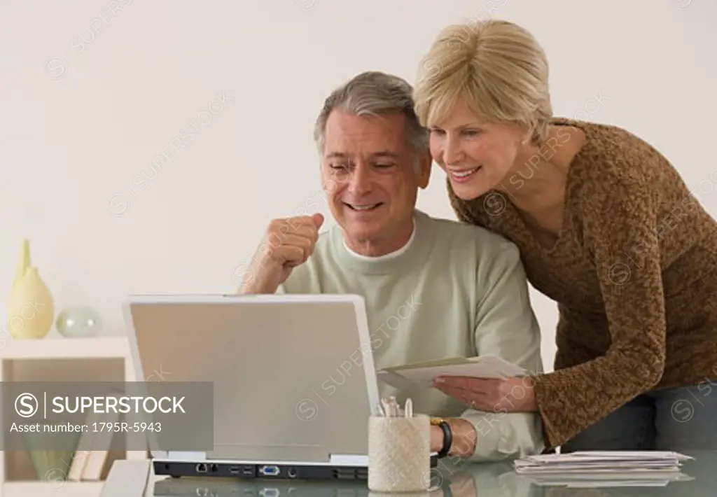 Senior couple smiling at laptop