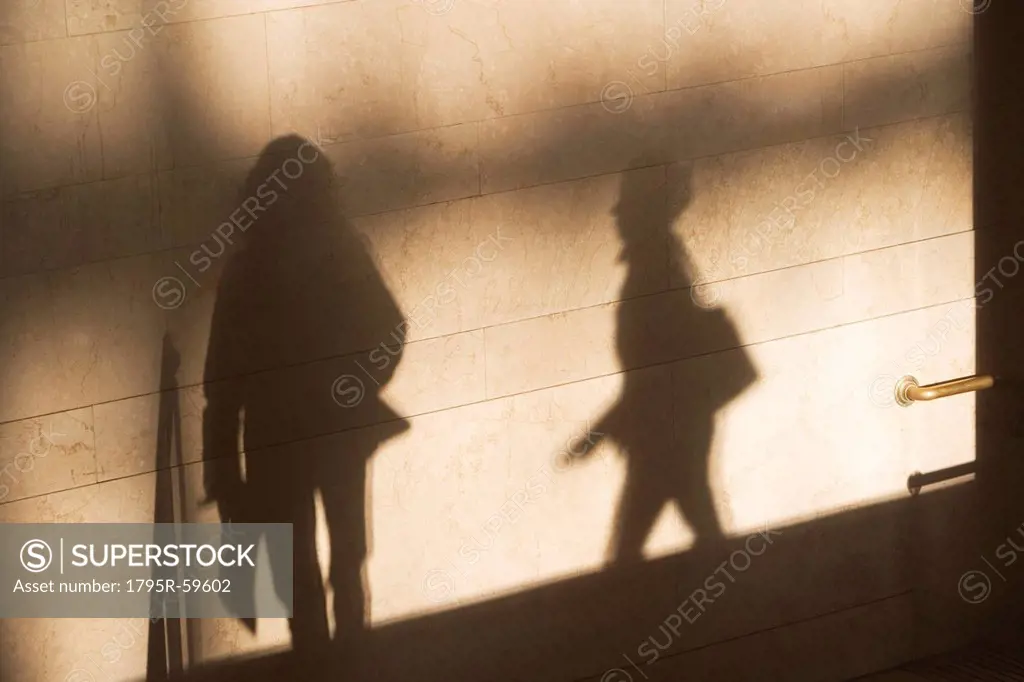 Shadow of two female pedestrians on sunlit wall