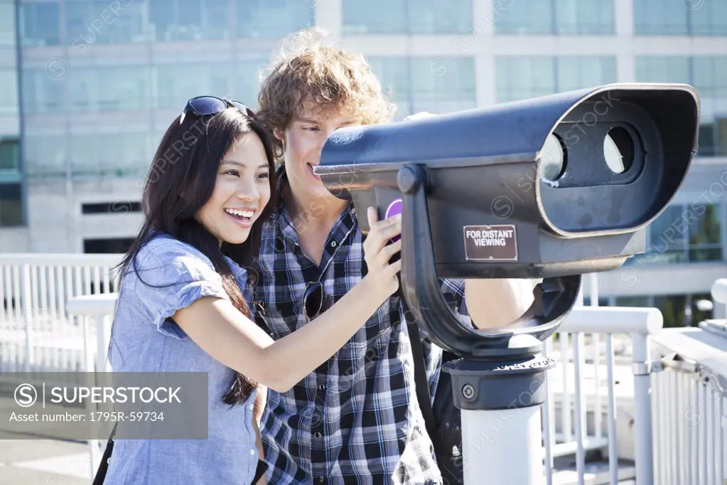 USA, Washington, Seattle, Couple looking through coin-operated binoculars