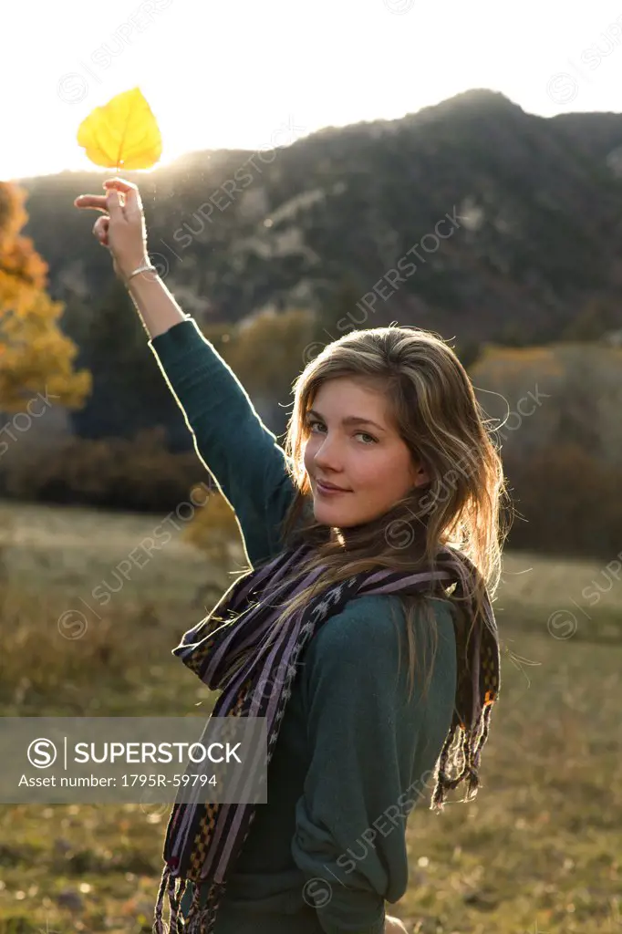 USA, Colorado, Portrait of young woman holding up leaf
