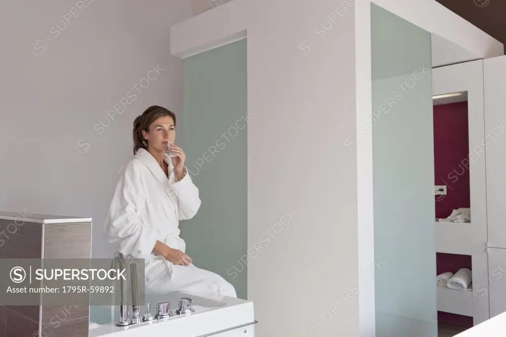Woman in bathrobe sitting on tub