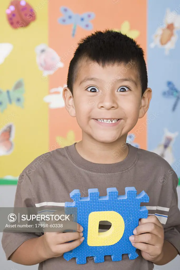 Smiling boy (6-7) holding letter D