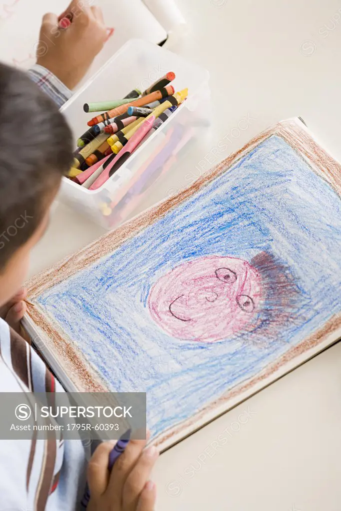 Boy (6-7) drawing in classroom