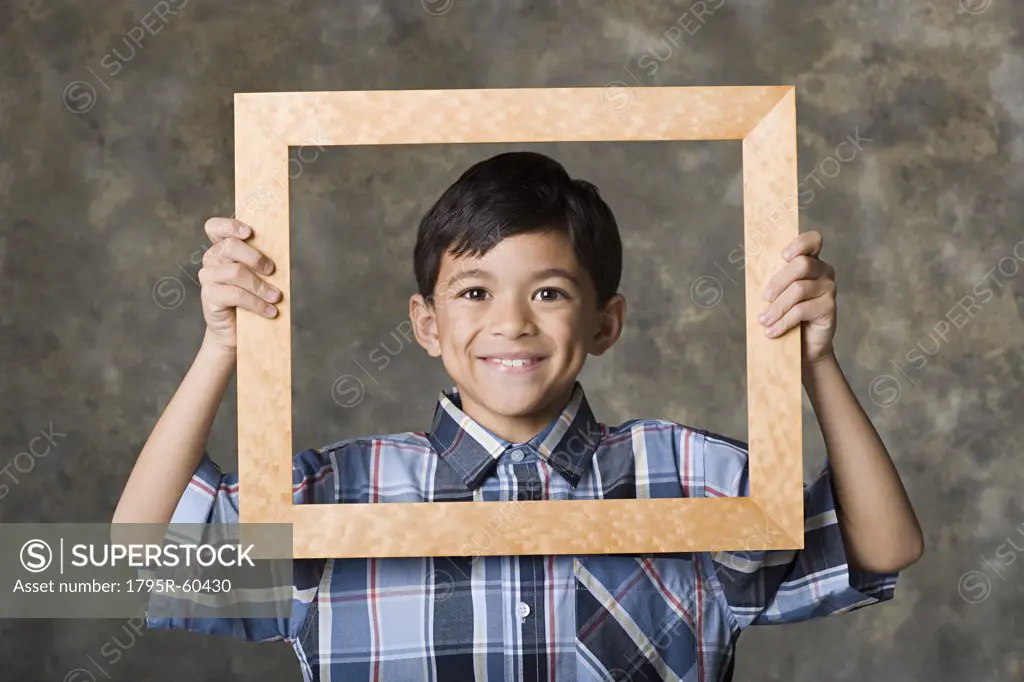 Portrait of smiling boy (8-9) looking through frame, studio shot