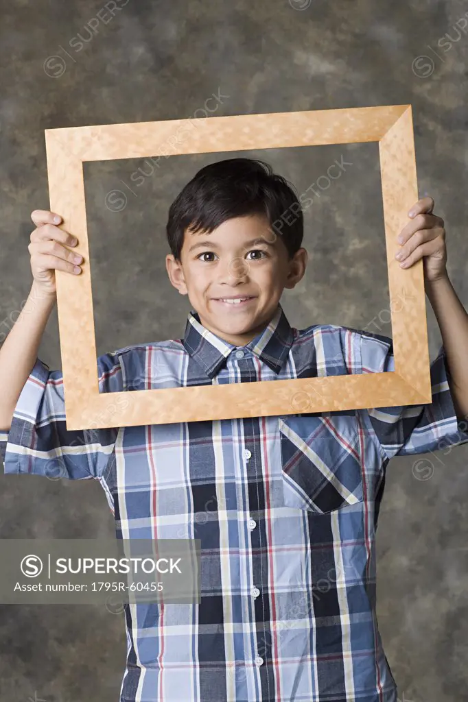 Portrait of smiling boy (8-9) looking through frame, studio shot