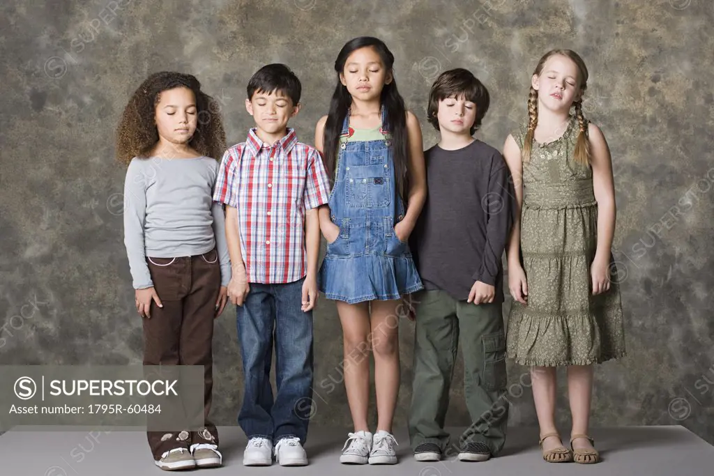Children (6-7, 8-9) standing together with eyes closed, studio shot