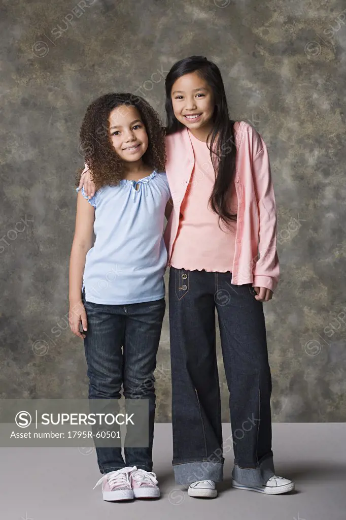 Two smiling girls (8-9) standing together, studio shot