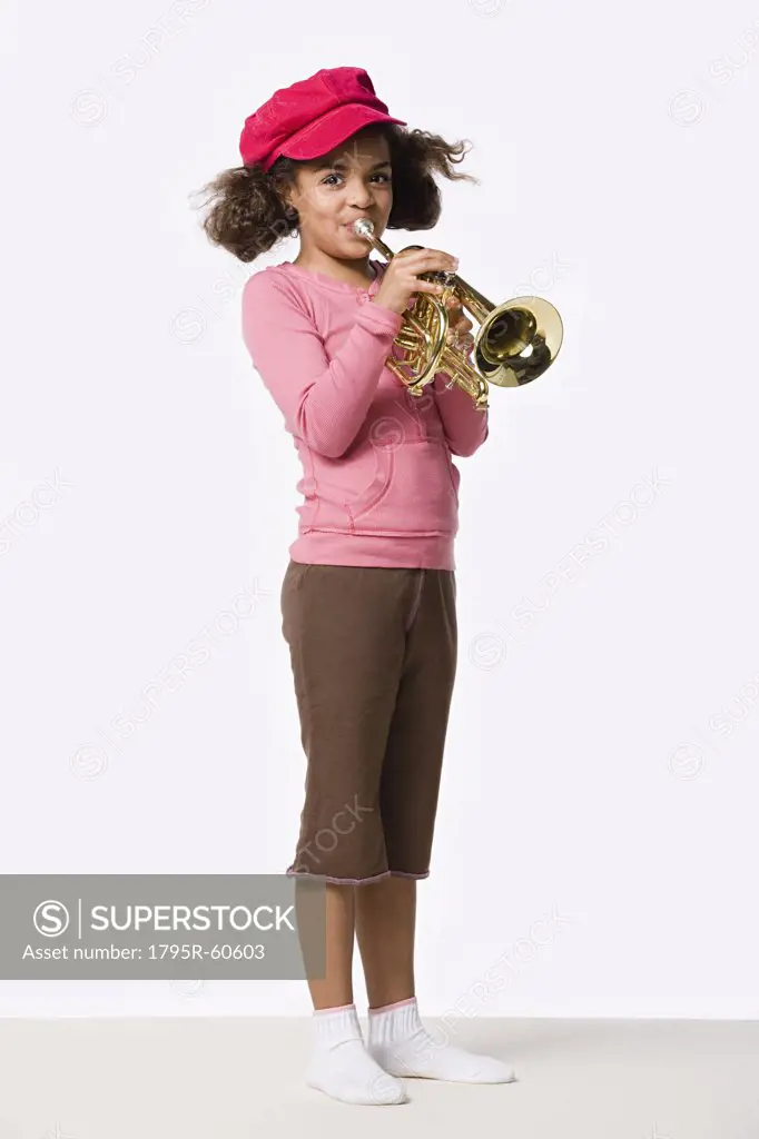 Studio portrait of girl (8-9) playing trumpet