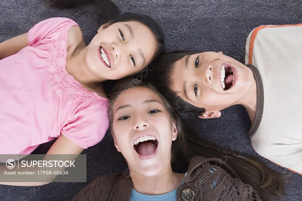 Portrait of laughing children (8-9, 10-11) lying on floor