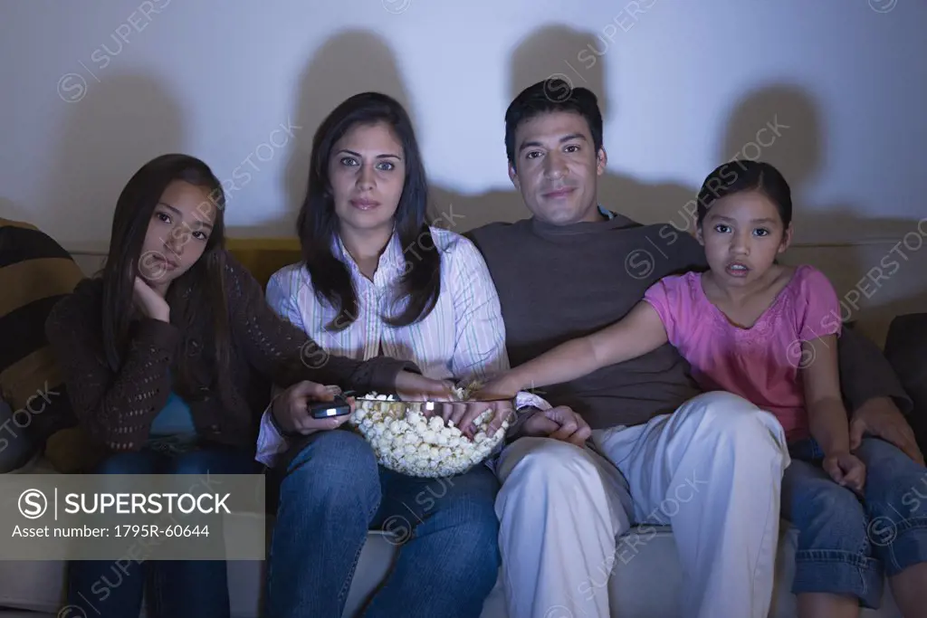 Family with two daughters (8-9, 10-11) watching tv on sofa