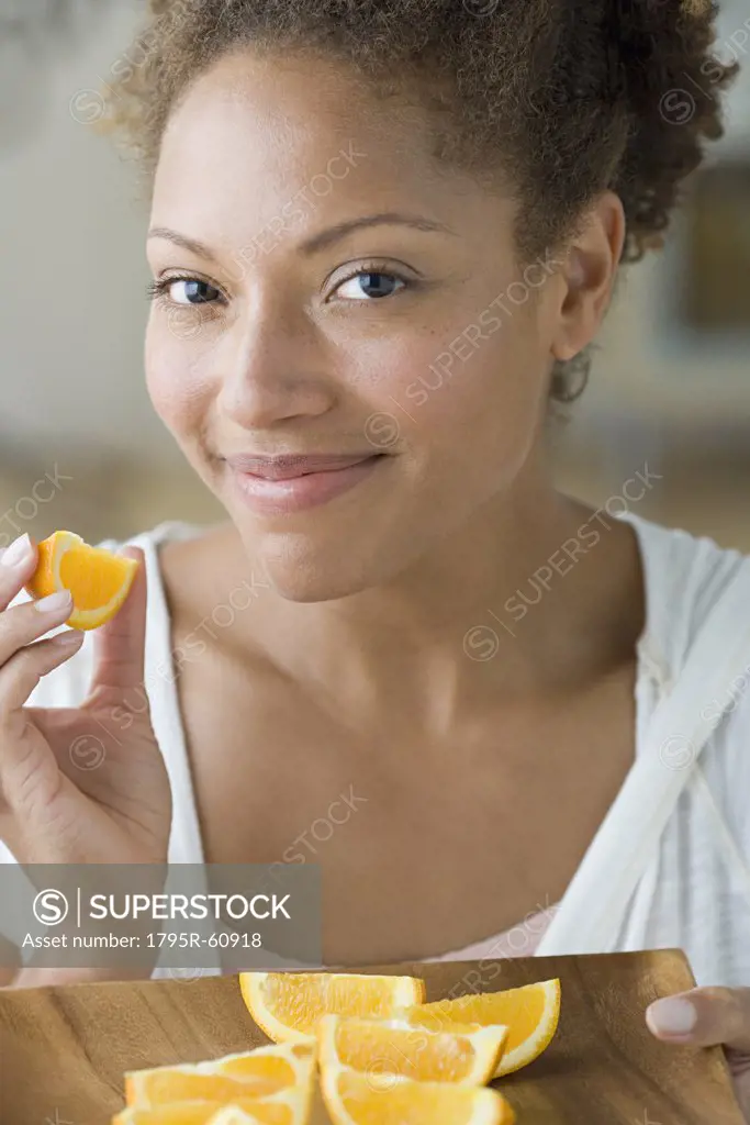 Portrait of attractive woman eating orange