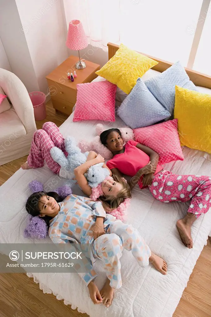 Three girls 10_11 lying on bed at slumber party