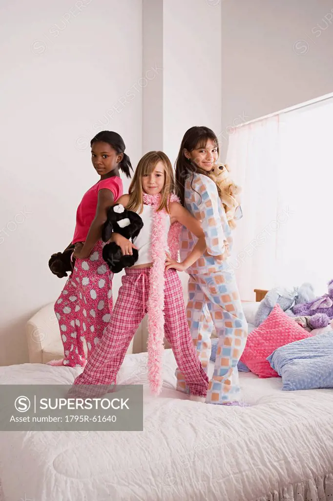 Portrait of three girls 10_11 standing on bed at slumber party