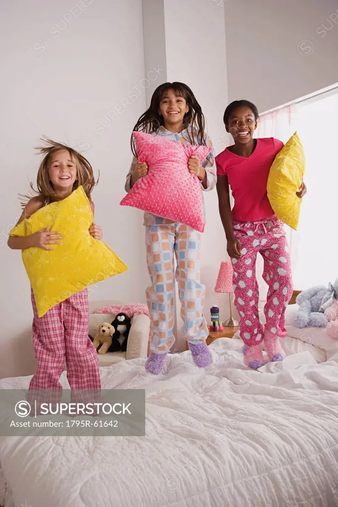 Portrait of three girls 10_11 jumping on bed at slumber party