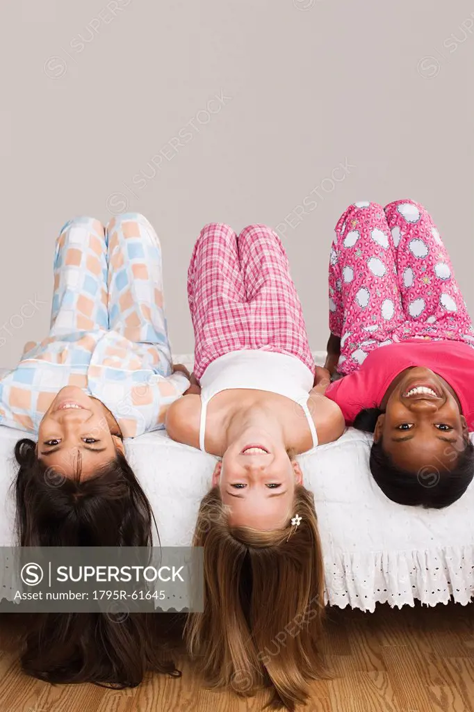 Portrait of three girls 10_11 lying on bed with heads down