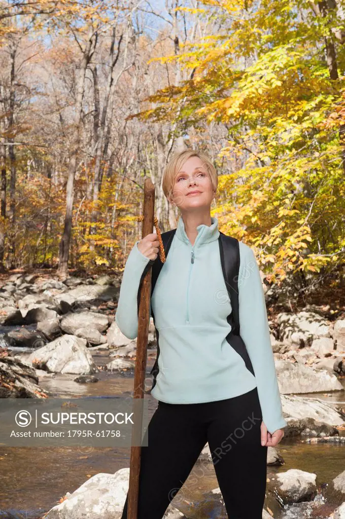 Female hiker standing by stream in forest