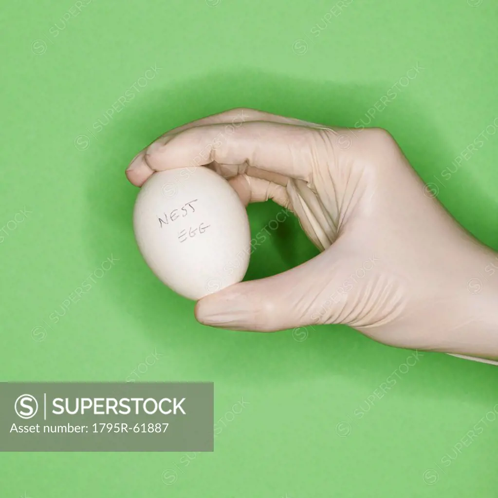 Hand in surgical glove holding egg