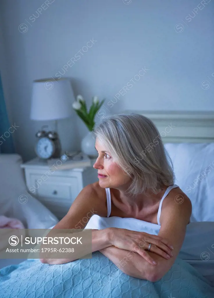 Senior woman sitting in bed and suffering from insomnia