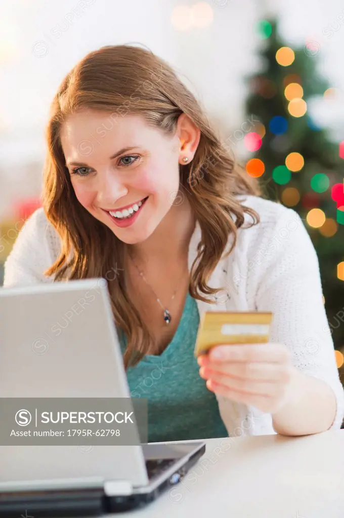 Young woman on_line shopping from home with Christmas tree on background