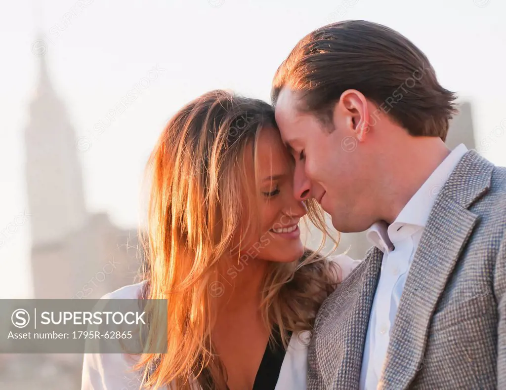 USA, New York, Long Island City, Close_up of happy young couple, Manhattan skyline in background