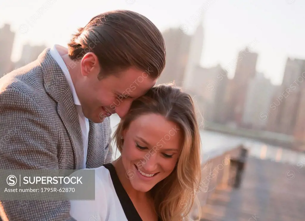 USA, New York, Long Island City, Young couple flirting on bridge, Manhattan skyline in background