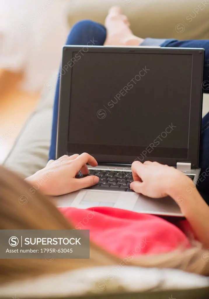Portrait of young woman with laptop in living room