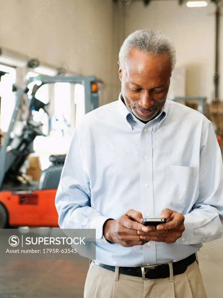 Businessman using phone in warehouse