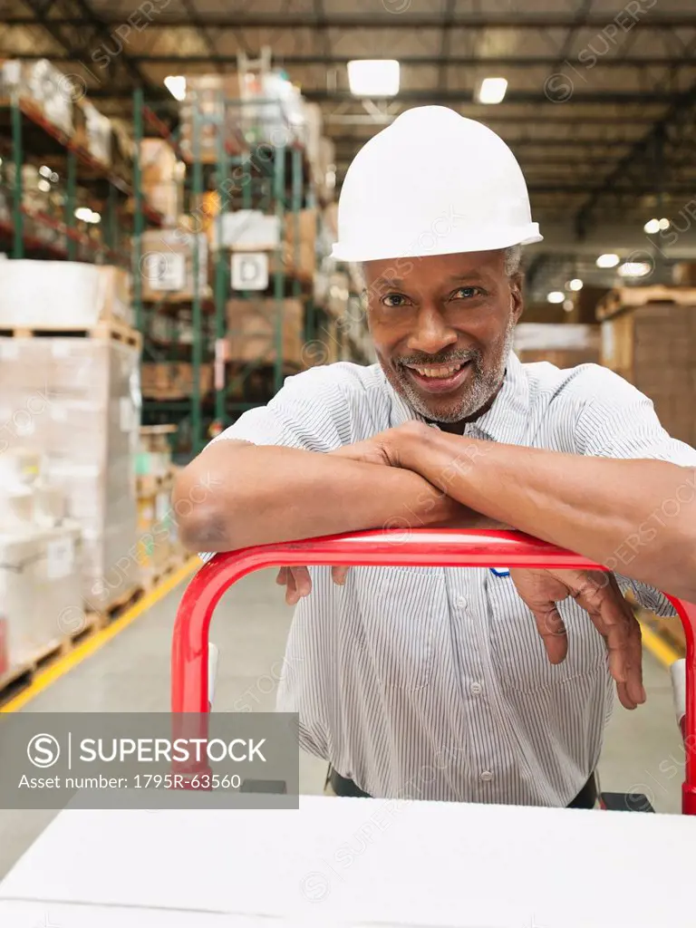 Portrait of man pushing hand truck in warehouse