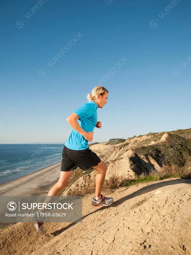 USA, California, San Diego, Man jogging along sea coast