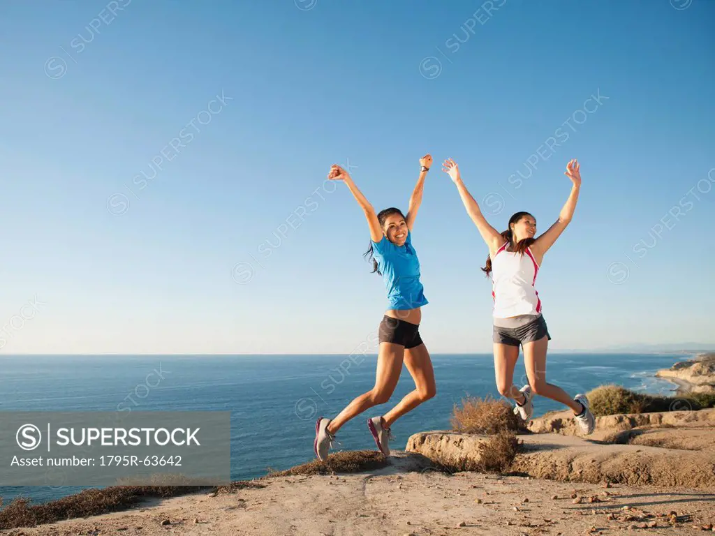 USA, California, San Diego, Two women jumping at sea coast