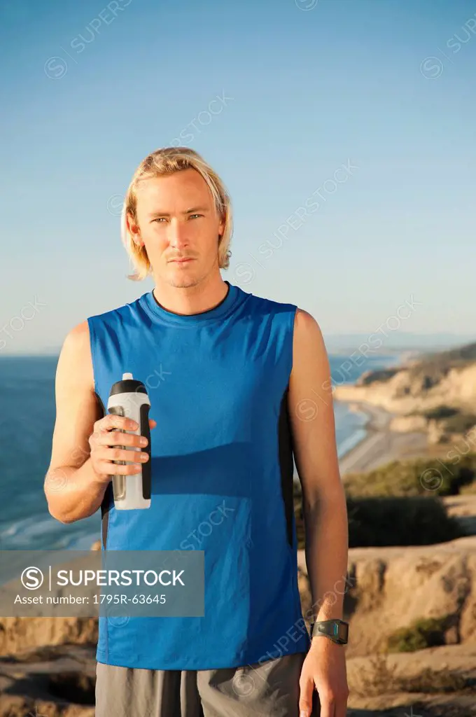USA, California, San Diego, Portrait of male jogger holding water bottle